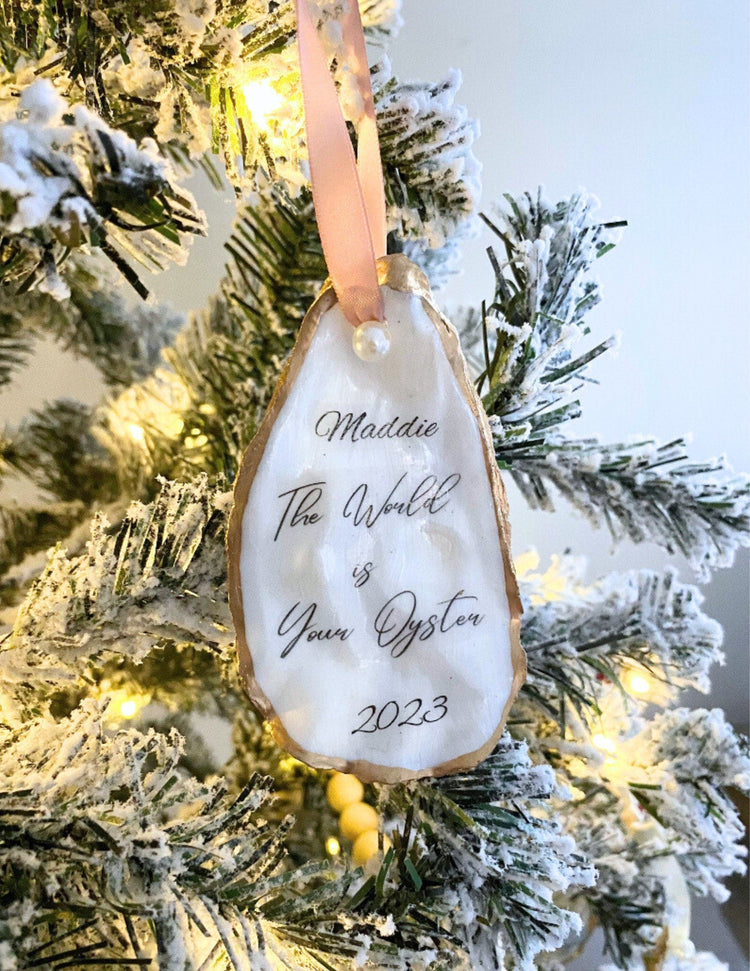 All natural handmade personalized oyster shell ornament with pearl paint and gold gild paint on edges adorned with ivory or rose gold satin ribbon and a cultured pearl