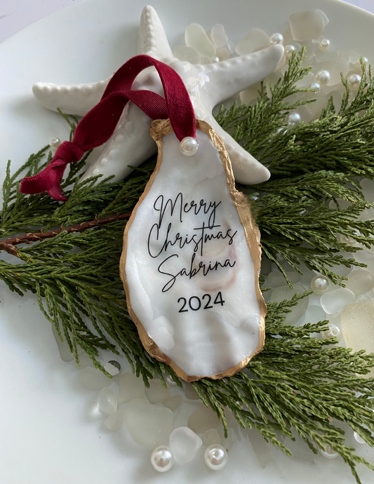 Oyster shell ornament with Merry Christmas wording, personalized date, gold trim, and red ribbon displayed as a holiday keepsake gift