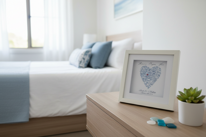 Framed heart-shaped map personalized artwork on a wooden coffee table in a bedroom setting.