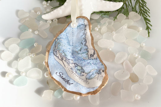 A personalized Sanibel Island oyster shell Christmas ornament with a map design, featuring a white and blue color scheme and the name 'SANIBEL' on the map.
