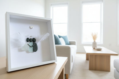 Two sea glass angels hugging one human in sea glass and pebble art.