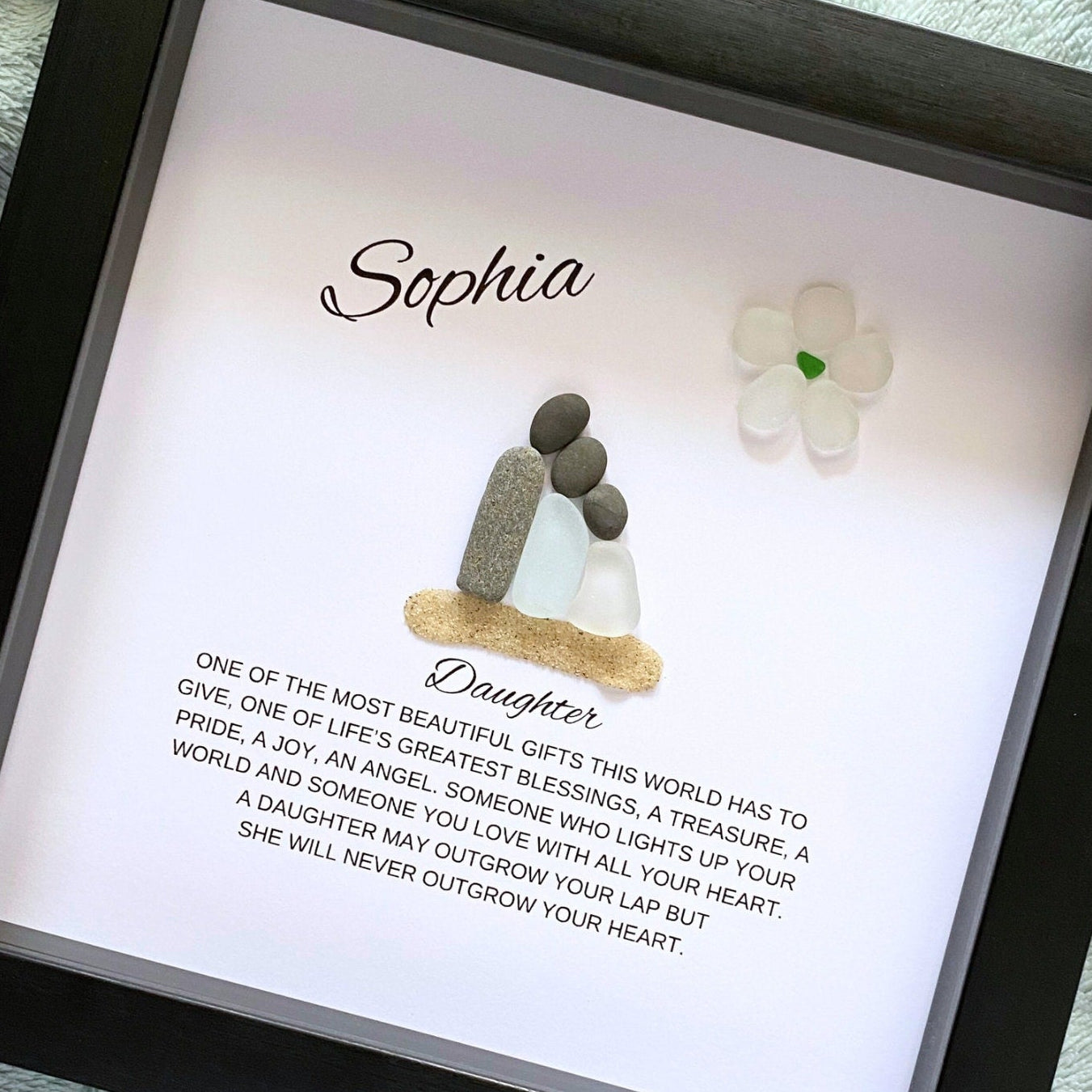 A personalized daughter gift featuring a framed shadowbox with sea glass and pebble art, with a personalized message and the name 'Sophia' inside the frame.