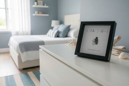 Framed artwork on a dresser in a bedroom with a bed and shelves in the background.