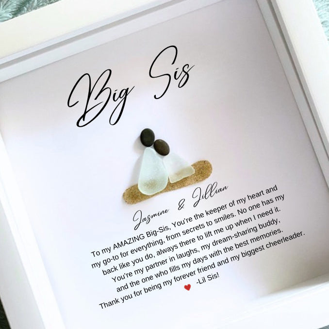 Personalized Big Sister gift with sea glass and pebble art, displayed in a white frame with a written message and a small sea glass figure.