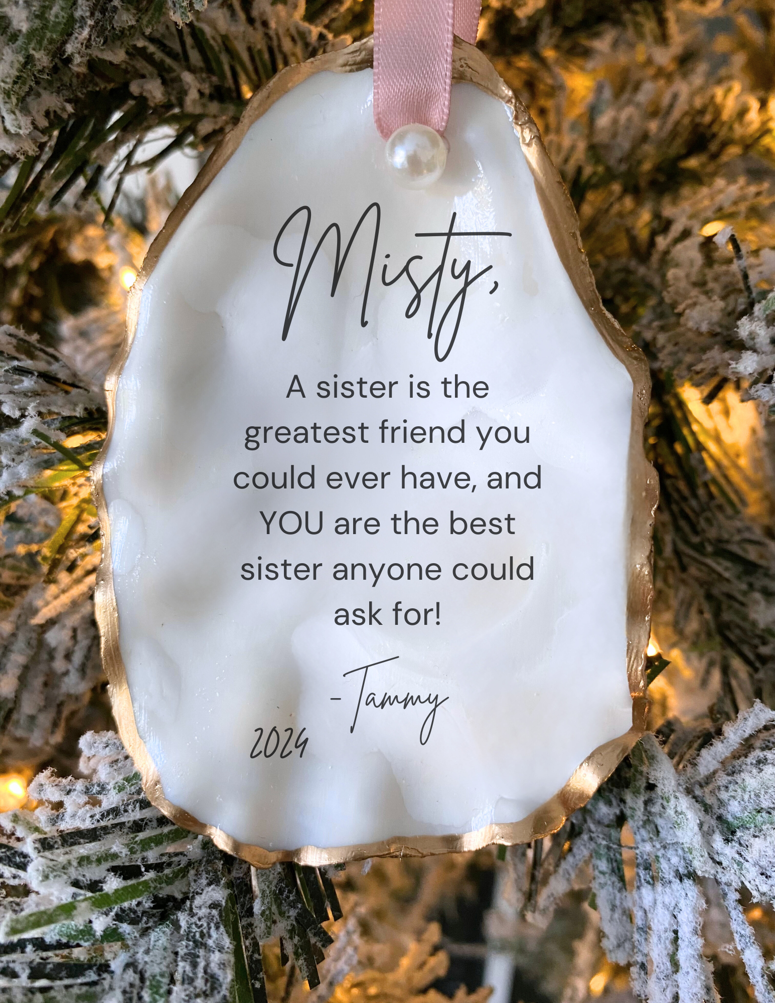 A personalized Christmas ornament oyster shell design, featuring a quote about being a sister, along with greenery and pearls embellishments.