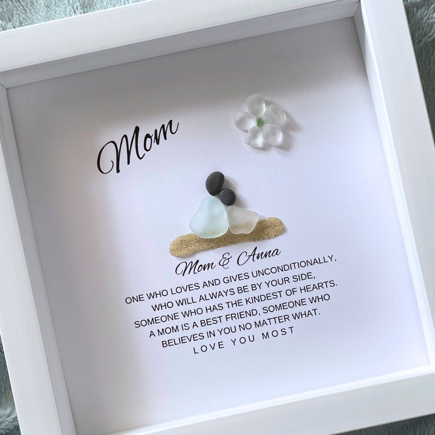 Mom and Daughter Sea glass figures with pebble heads sitting on sand with their names below and a little quote. On top it says "Mom" with a glass flower.