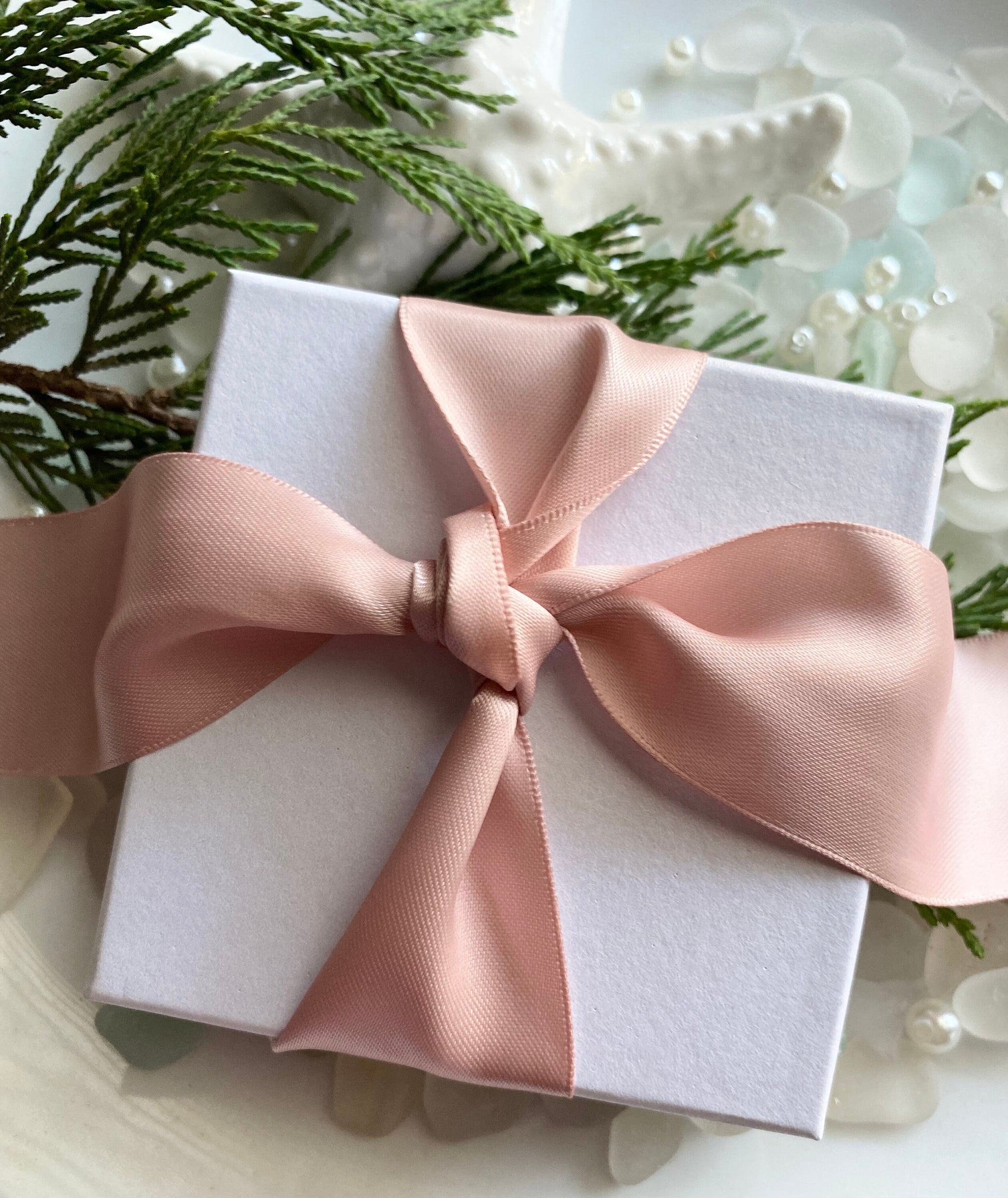 White gift box wrapped in a rose gold satin ribbon