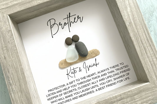 Framed artwork with pebbles and text for a brother, featuring a light wood frame.