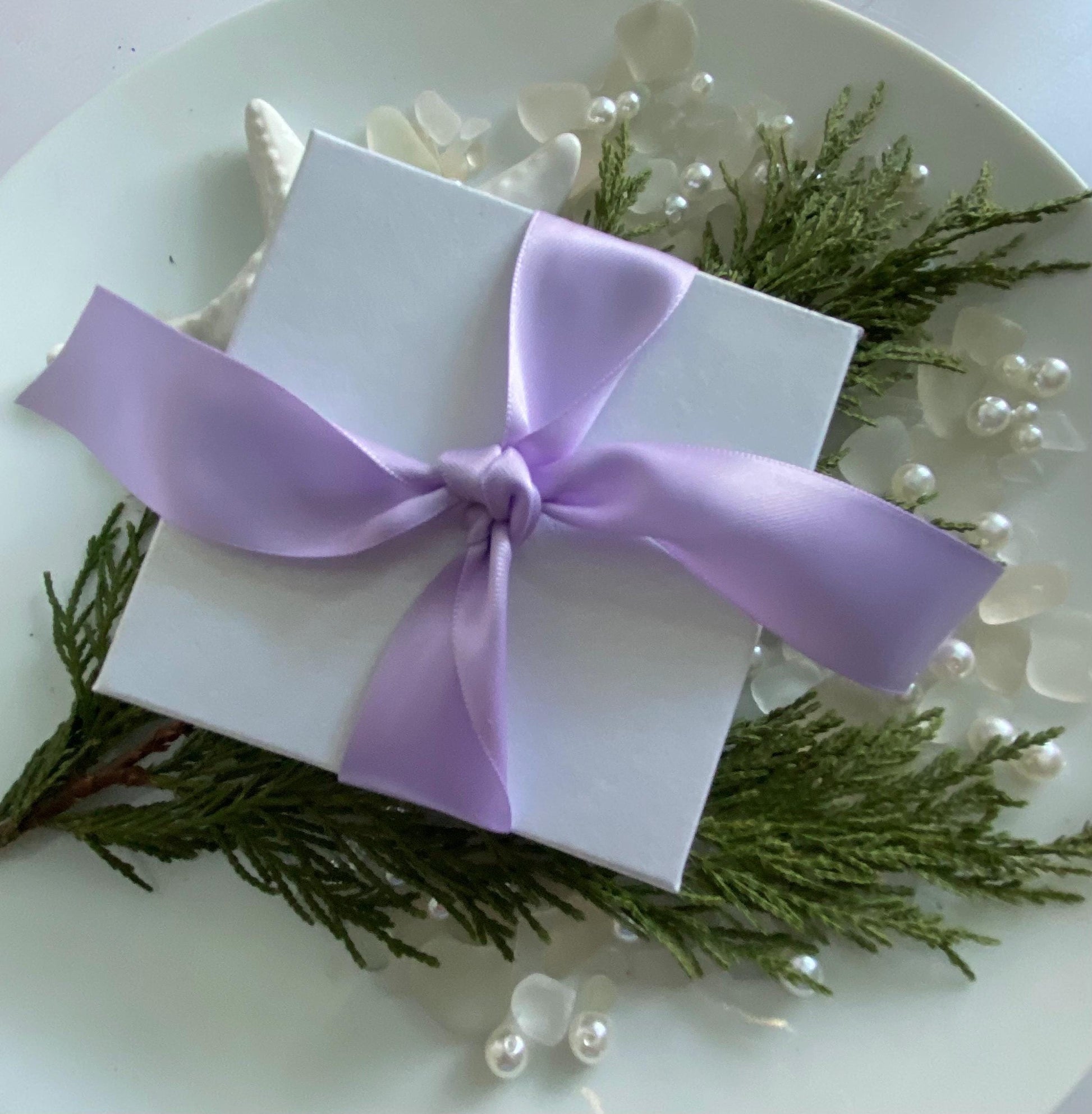 White gift box wrapped in a lavender satin ribbon