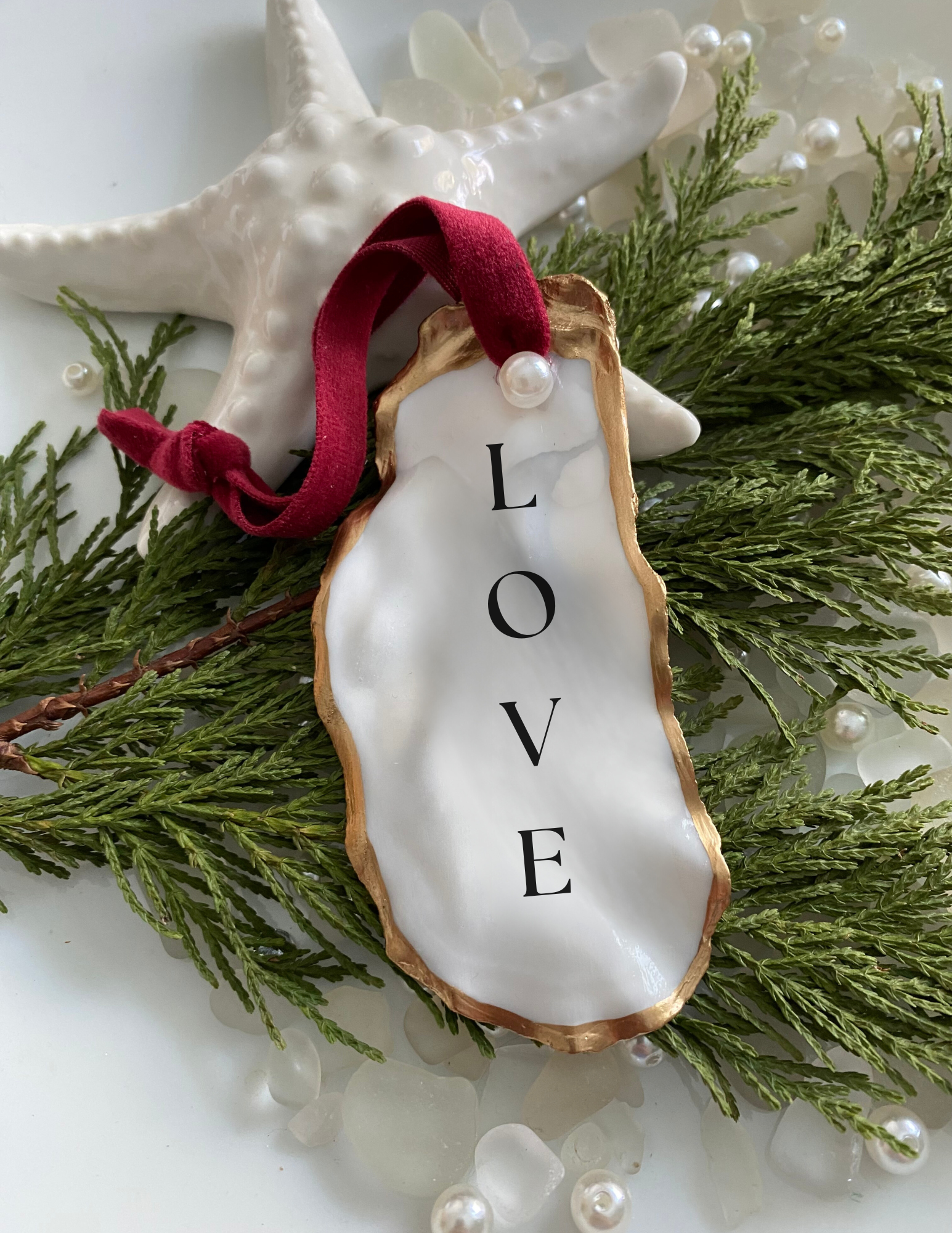 Love oyster shell ornament featured on plate with tree pearls and sea glass