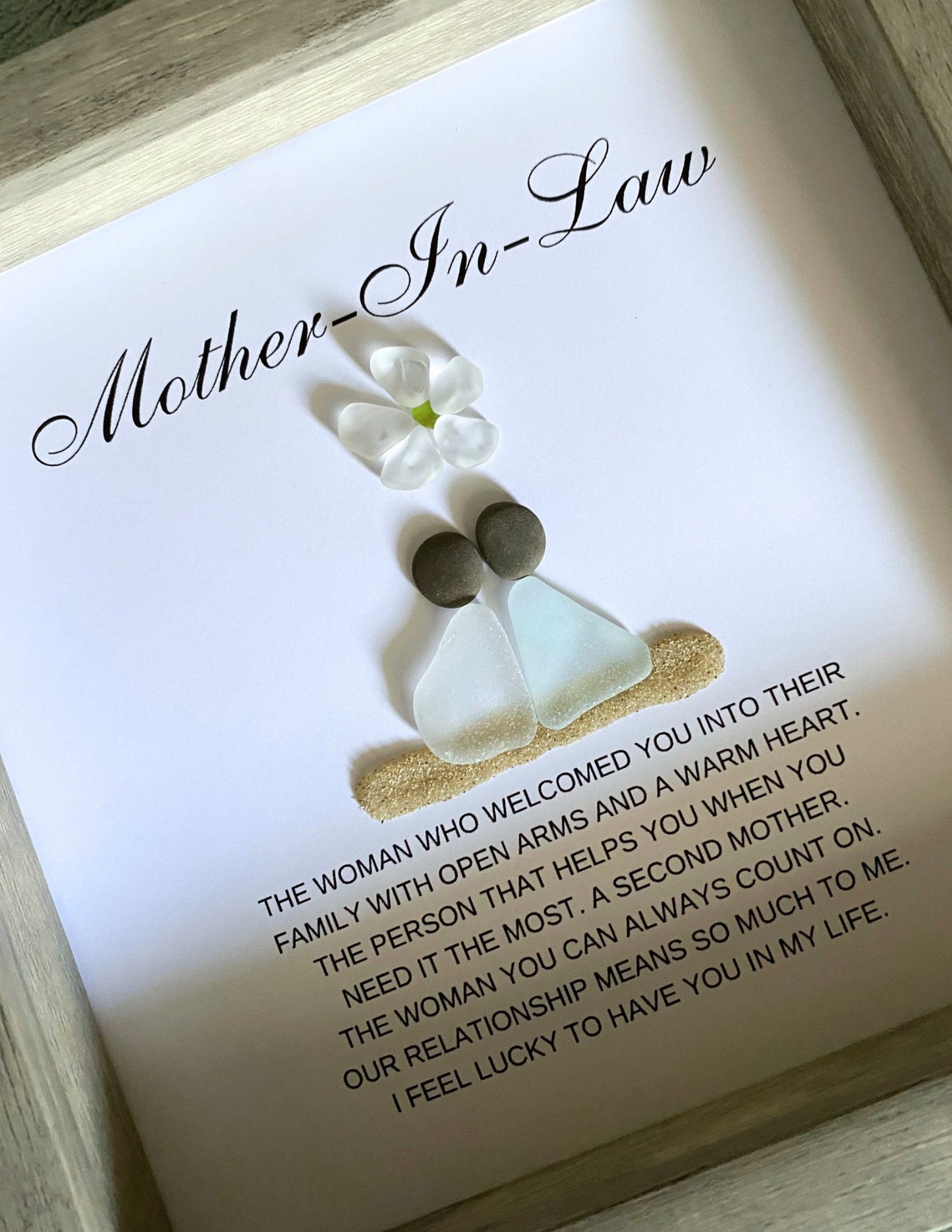 Personalized framed sea glass art for mother-in-law featuring two figures, a small glass flower, names, and custom message in a 9x9 shadow box.
