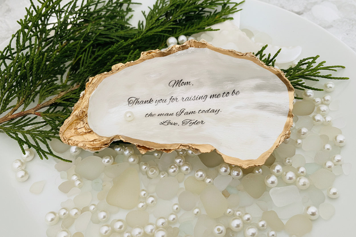Oyster shell with engraved message surrounded by greenery and pearls