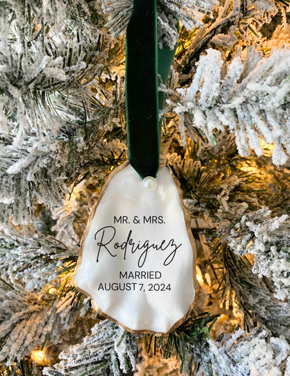 Personalized oyster shell ornament with engraved text hanging on a christmas tree
