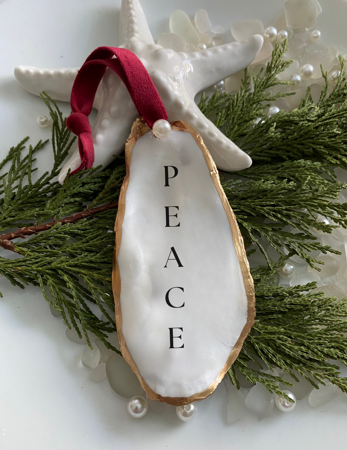 peace oyster shell ornament featured on plate with tree pearls and sea glass