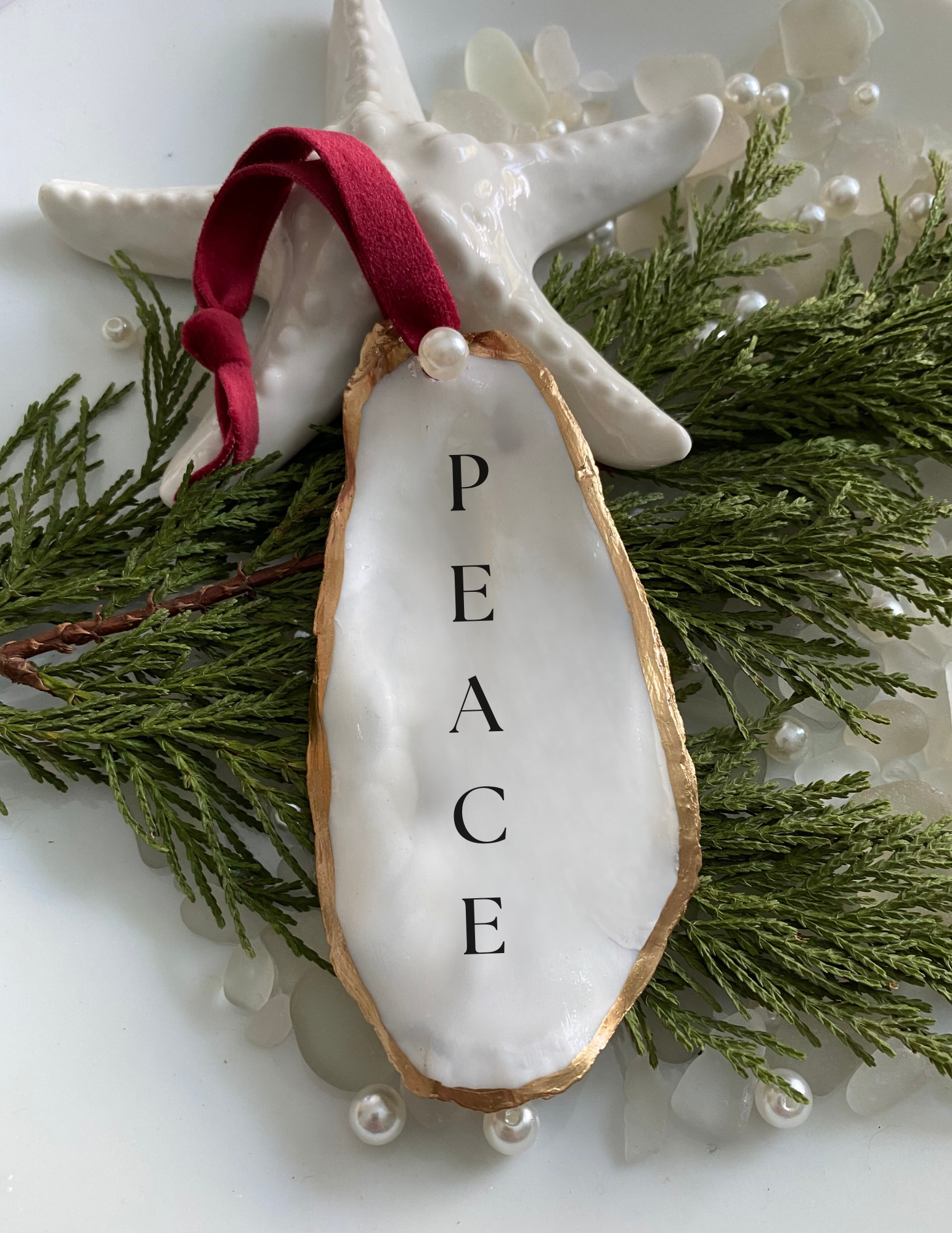 peace oyster shell ornament featured on plate with tree pearls and sea glass