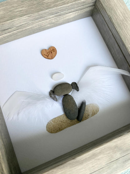 A personalized dog memorial gift featuring a white sea glass and pebble art piece with a shadowbox frame.