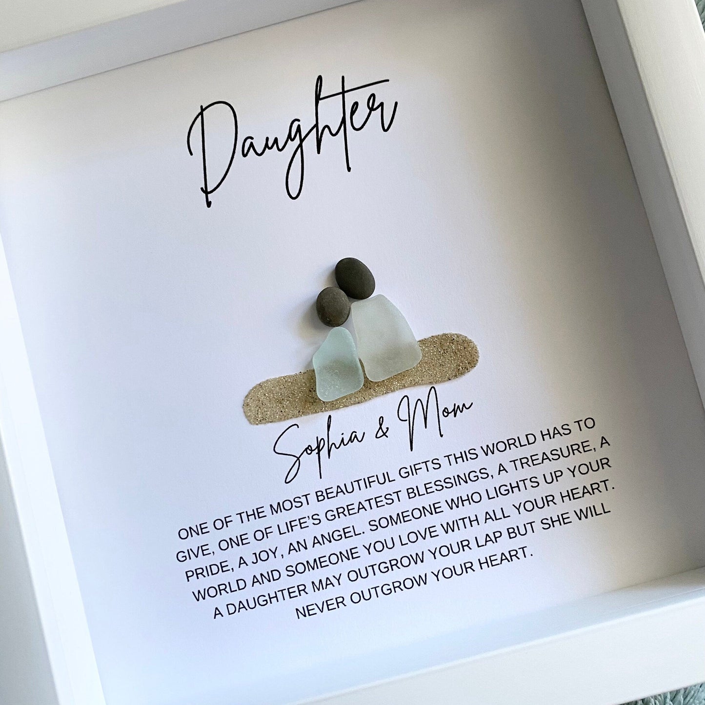 A framed pebble art daughter gift with personalized text and sea glass figures.
