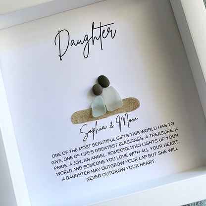 A framed pebble art daughter gift with personalized text and sea glass figures.