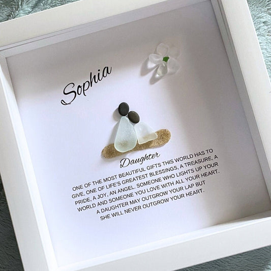 A framed pebble art piece with sea glass and stones, personalized with the name 'Sophia' and a message from a mother to her daughter.