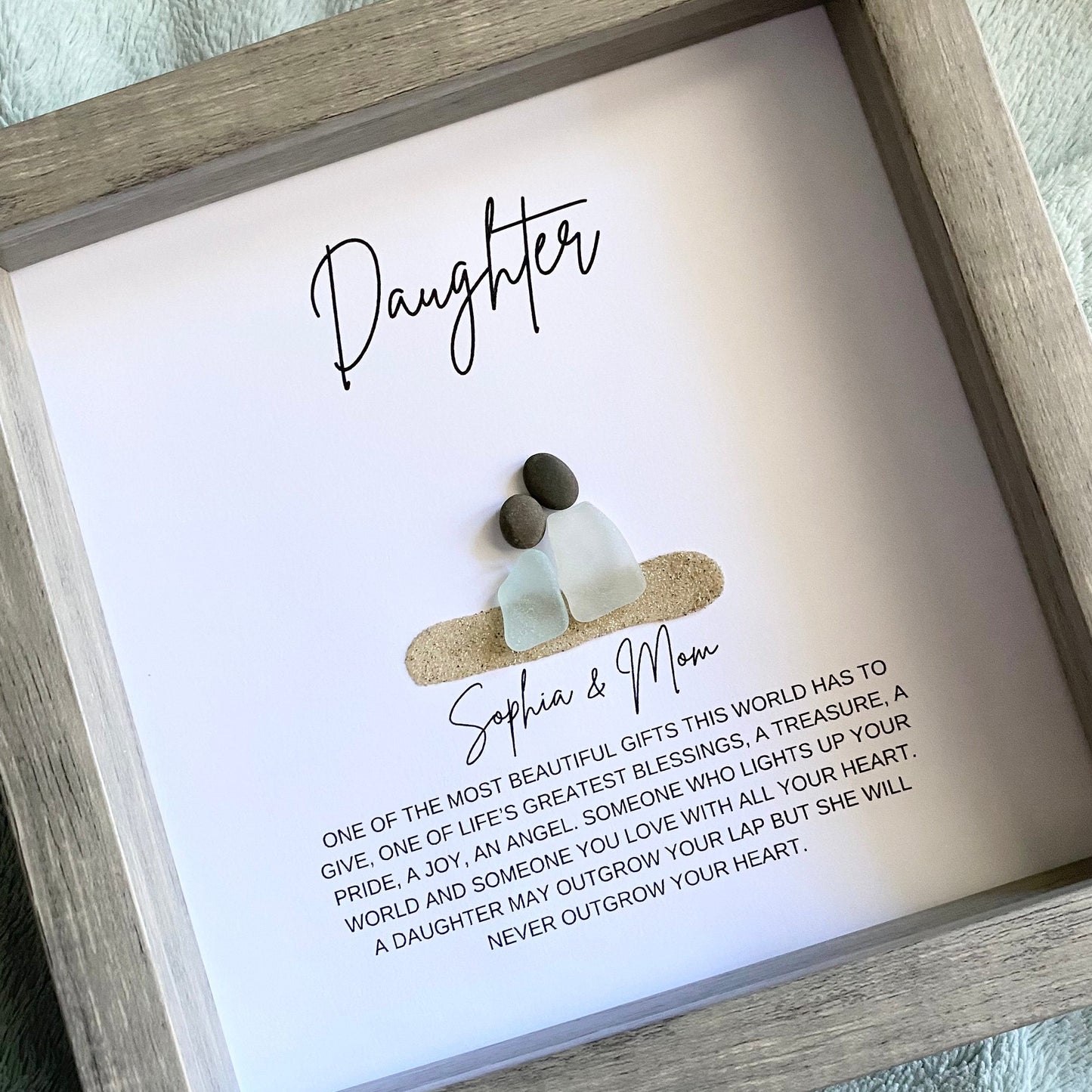 Framed artwork with 'Daughter' and 'Sophia & Mom' text, featuring two small figures and a quote.