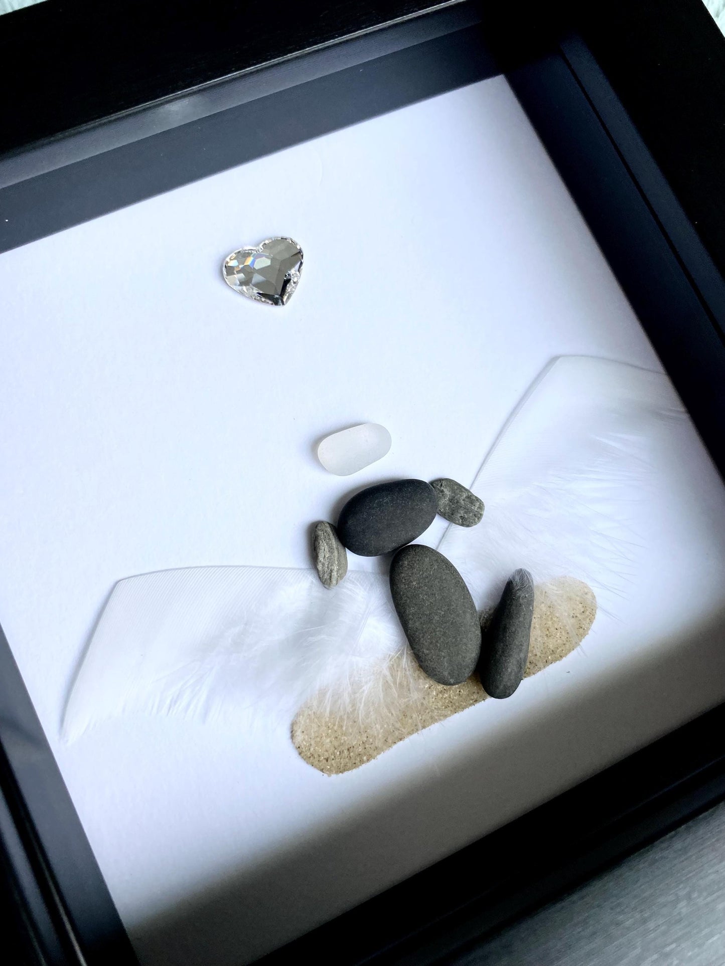 A personalized dog memorial gift featuring a white sea glass and pebble art piece with a shadowbox frame.
