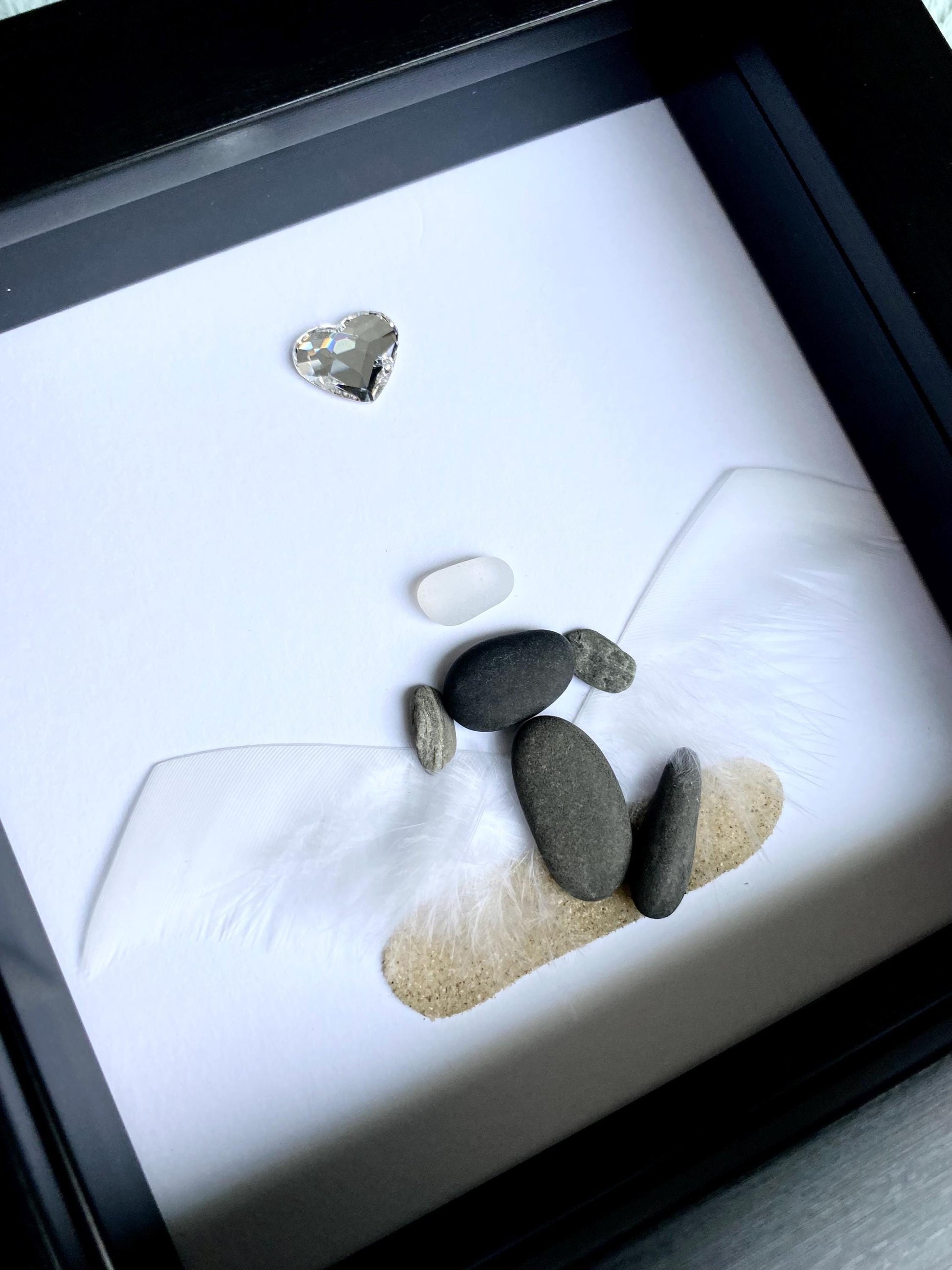 A personalized dog memorial gift featuring a white sea glass and pebble art piece with a shadowbox frame.