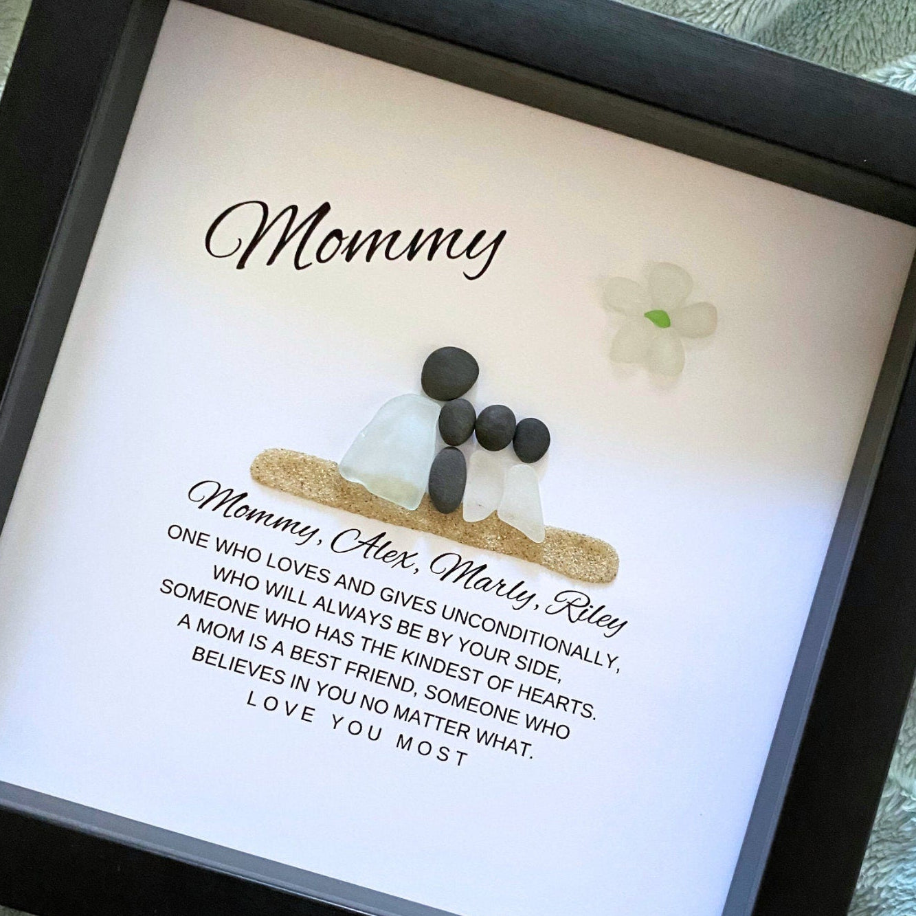 Mom and Daughter Sea glass figures with pebble heads sitting on sand with their names below and a little quote. On top it says "Mom" with a glass flower.