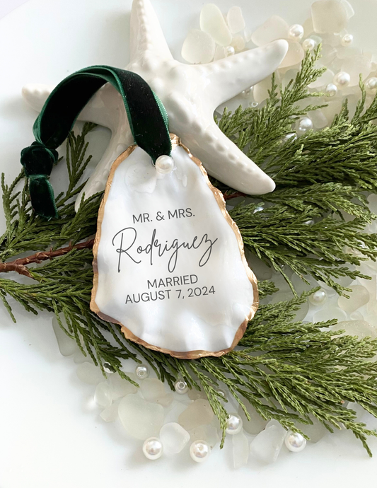 Personalized oyster shell ornament with engraved text on a decorative background 