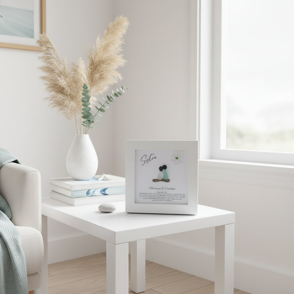 White side table with a vase of pampas grass and a framed picture in a minimalistic living room.