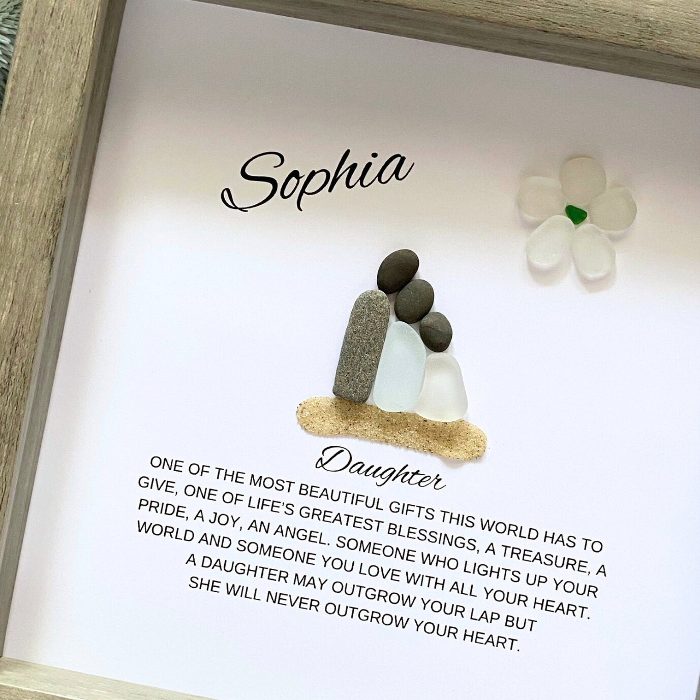 A personalized daughter gift featuring a framed shadowbox with sea glass and pebble art, with a personalized message and the name 'Sophia' inside the frame.