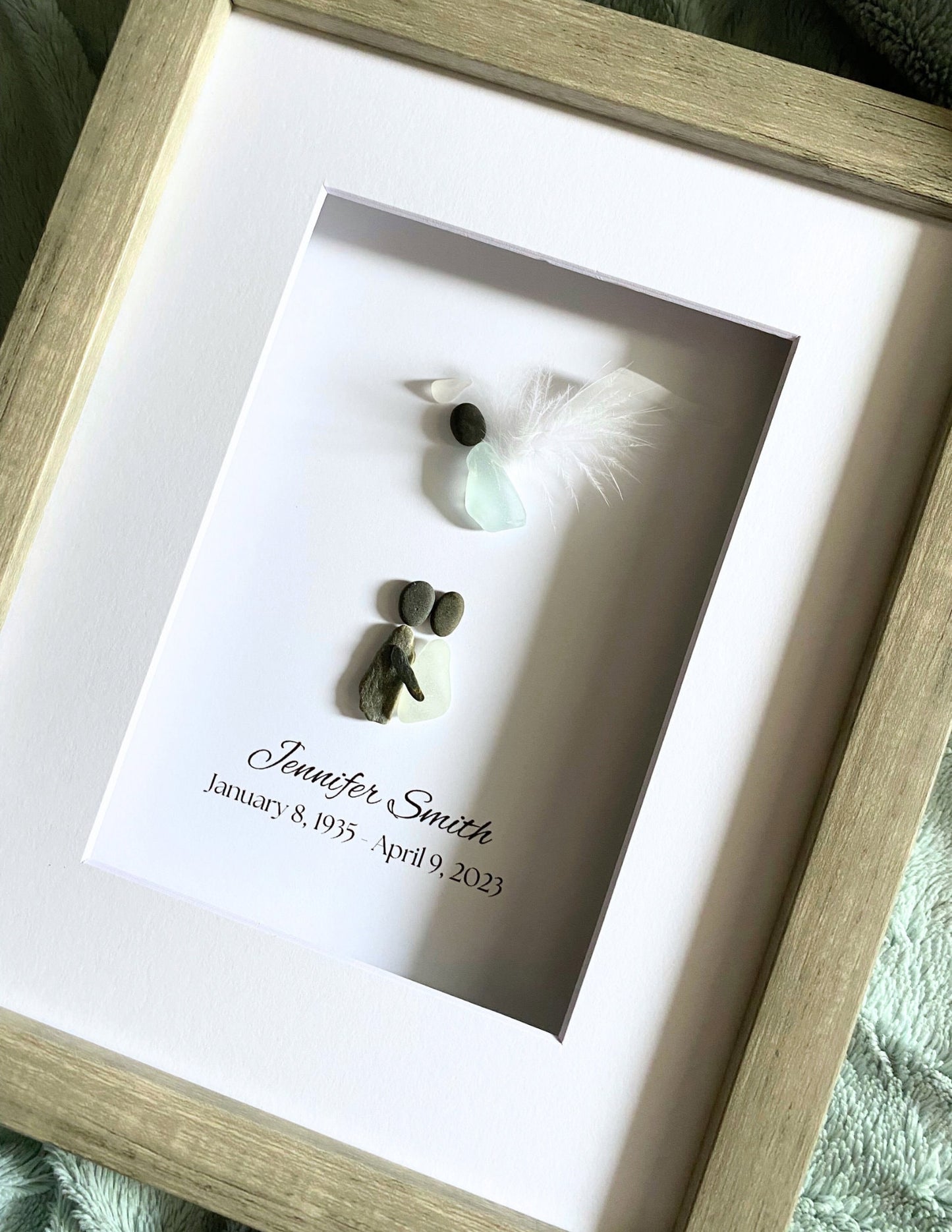 Framed memorial with a name and dates, featuring small decorative elements.
